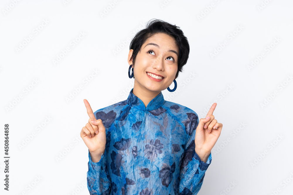 Young Vietnamese woman with short hair wearing a traditional dress over isolated white background pointing up a great idea Young Vietnamese woman with short hair wearing a traditional dress over isolated white background pointing up a great idea