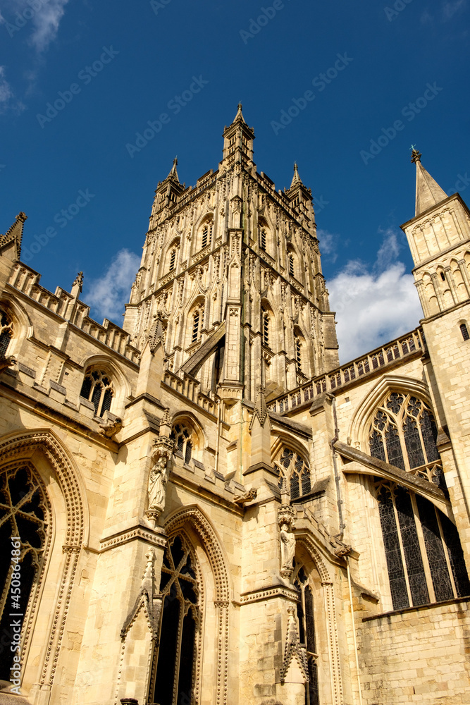 Gloucester Cathedral looking up at the tower against a blue sky.
