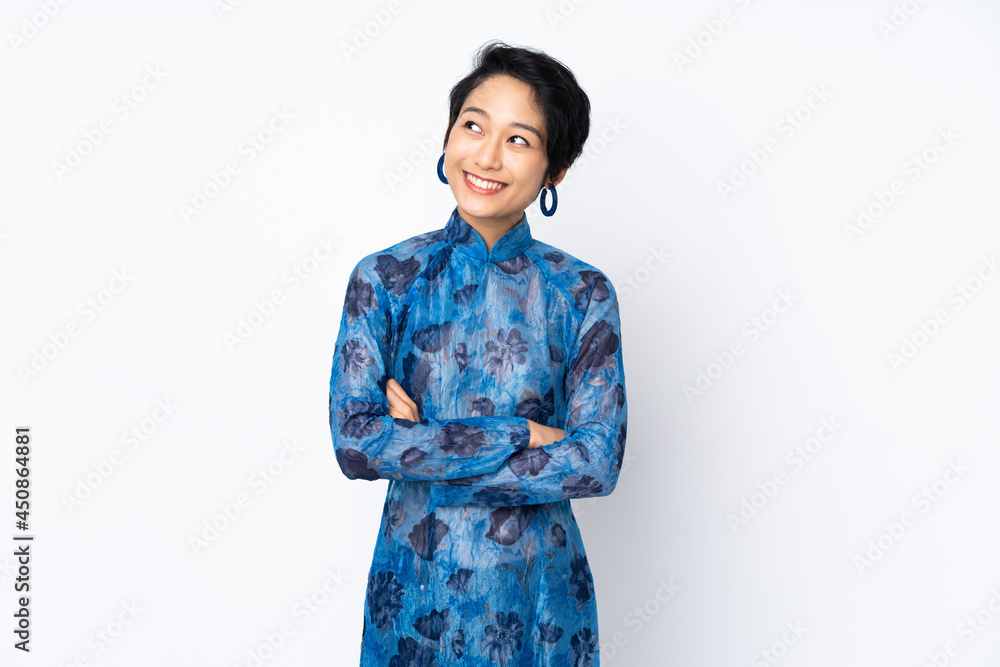 Young Vietnamese woman with short hair wearing a traditional dress over isolated white background looking up while smiling Young Vietnamese woman with short hair wearing a traditional dress over isolated white background looking up while smiling