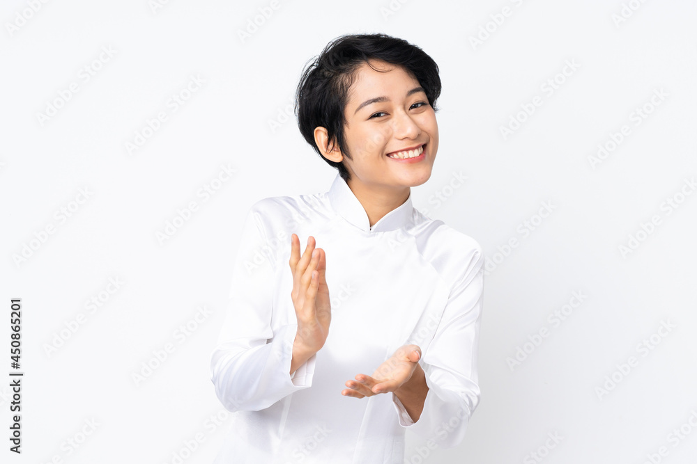Young Vietnamese woman with short hair wearing a traditional dress over isolated white background applauding after presentation in a conference Young Vietnamese woman with short hair wearing a traditional dress over isolated white background applauding after presentation in a conference