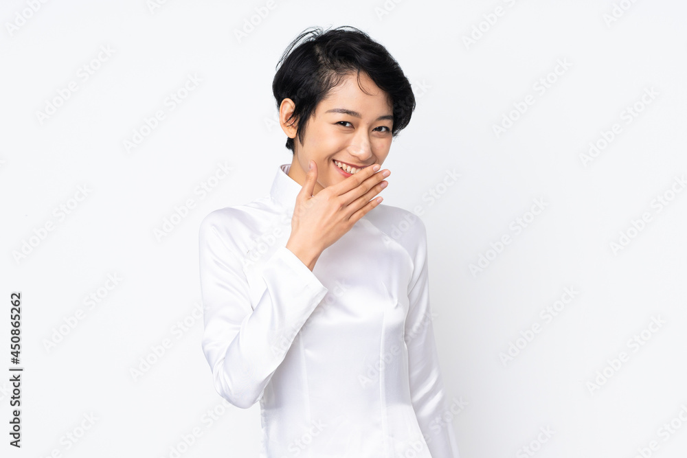 Young Vietnamese woman with short hair wearing a traditional dress over isolated white background happy and smiling covering mouth with hand Young Vietnamese woman with short hair wearing a traditional dress over isolated white background happy and smiling covering mouth with hand