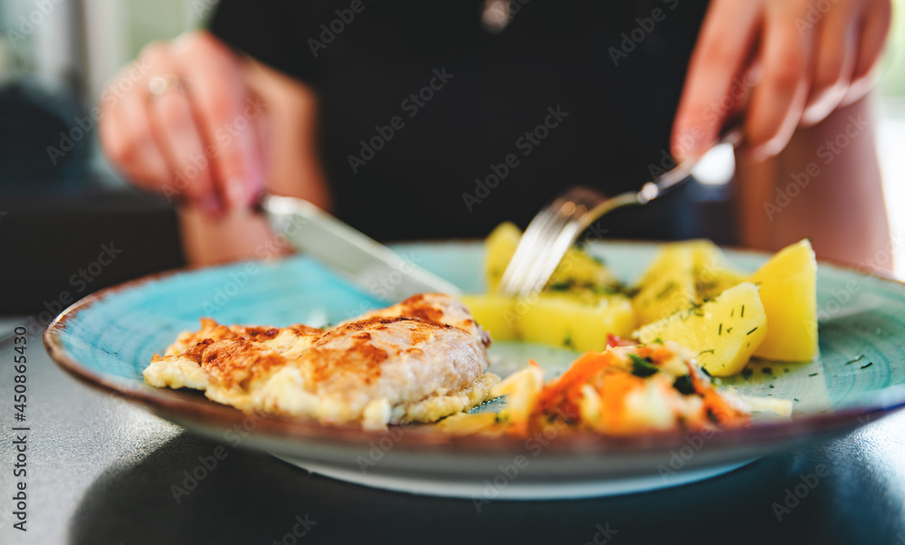 woman hand holding fork and knife eat chicken meat with potato in a plate
