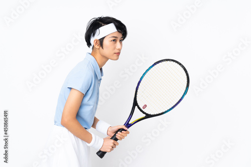 Young Vietnamese tennis player woman over isolated white wall playing tennis © luismolinero