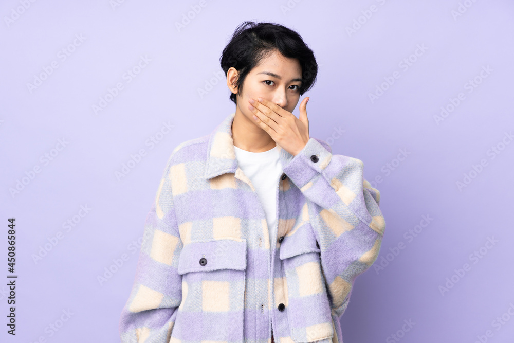 Young Vietnamese woman with short hair over isolated background covering mouth with hand Young Vietnamese woman with short hair over isolated background covering mouth with hand