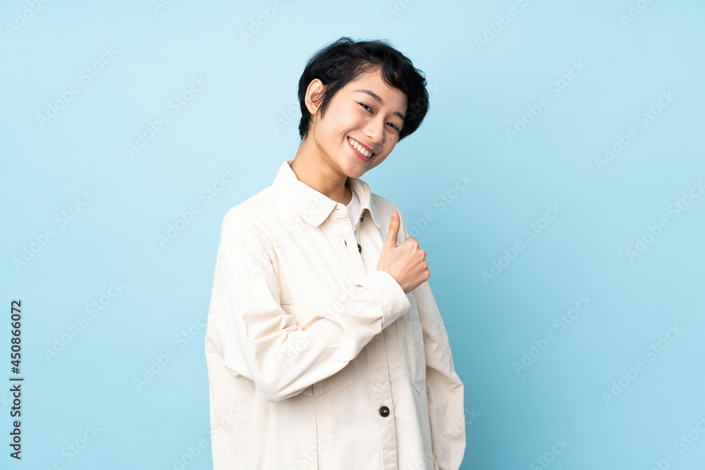 Young Vietnamese woman with short hair over isolated background giving a thumbs up gesture Young Vietnamese woman with short hair over isolated background giving a thumbs up gesture
