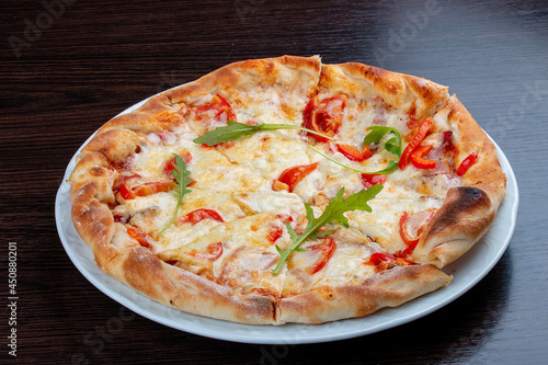 Pizza with tomatoes, peppers and mozzarella. On a wooden background