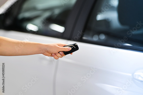 Women's hand presses on the remote control car to lock her car. New technology car keys remote concept. 
