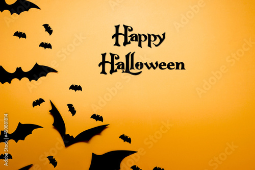 Happy Halloween banner. Bats flying in the sunset. Holiday concept with black and orange colors. Halloween party invitation. Happy Halloween card. 