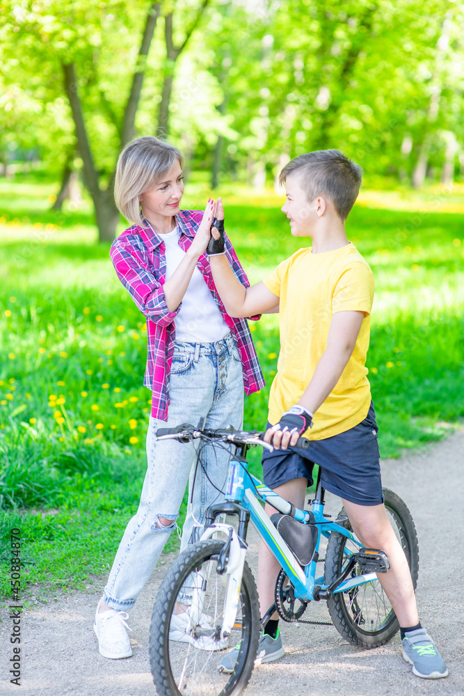 Obraz premium Mom and her young son give high five while cycling in the park