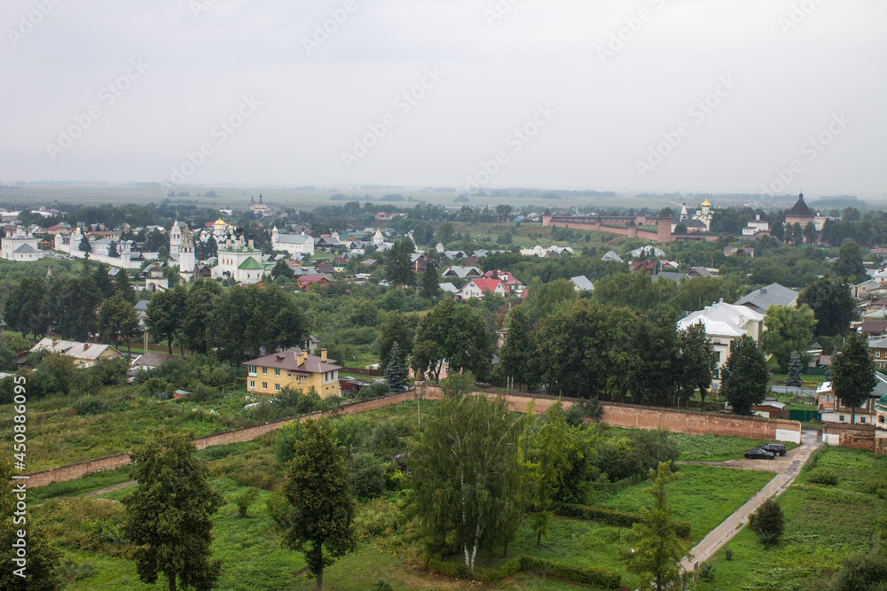 Panoramic top view of the historic old town of Suzdal with the roofs of houses and green foliage of trees on a cloudy summer day