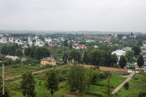 Panoramic top view of the historic old town of Suzdal with the roofs of houses and green foliage of trees on a cloudy summer day