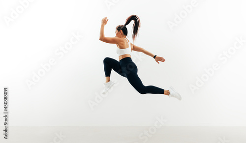 Female athlete running and jumping against white backgroung
