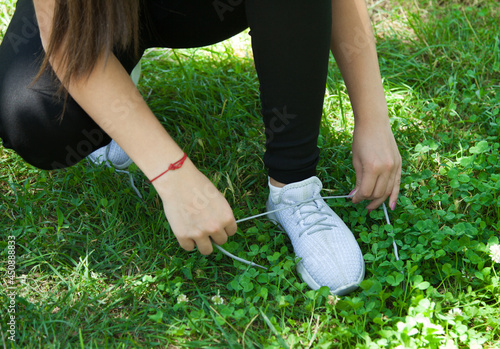  Woman runner tying her sneakers shoes. Outdoors.