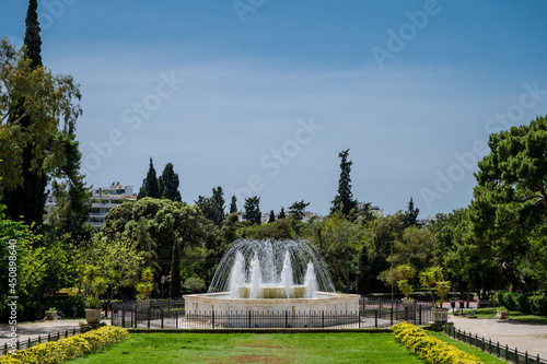 A fountain in national gardens in Athens on a hot summer day. Fresh cool water. Green plants and trees.
