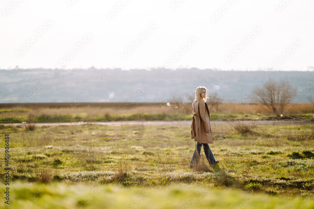 Stylish woman in coat enjoys nature. Autumn weather. People, freedom, lifestyle, travel, fashion concept.