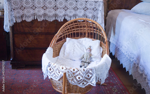 Antique wicker cradle with a doll and handmade lace photo