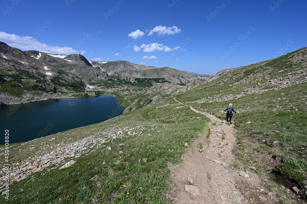 Fototapeta premium Woman descends King Lake Trail in Indian Peaks Wilderness in Arapaho National Forest, Colorado on clear sunny summer afternoon.