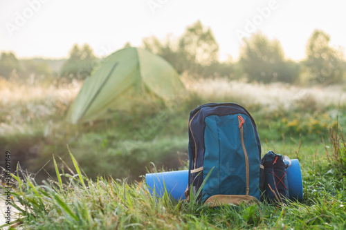 Sports backpack with a rug about a tourist tent on the background of nature and forest. photo