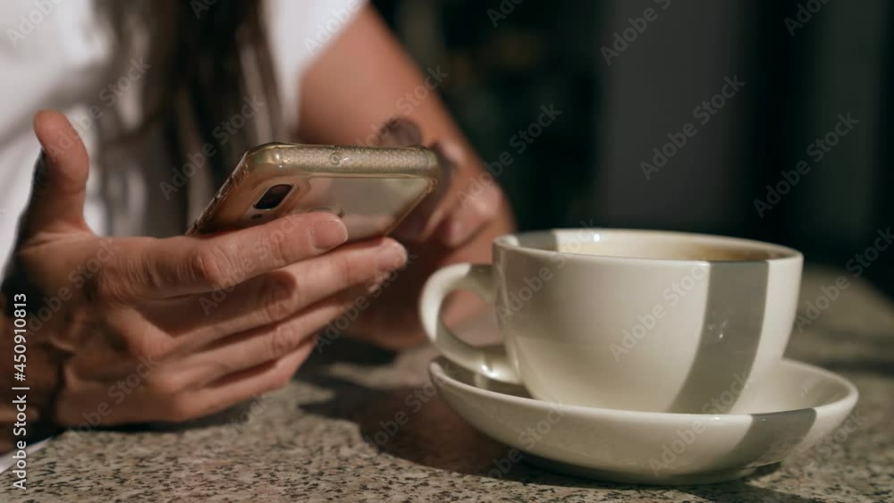 woman is surfing internet and viewing social networking by cellphone in cafe, closeup of hands woman is surfing internet and viewing social networking by cellphone in cafe, closeup of hands