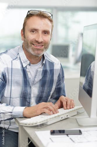 man is typing keyboard of the computer in the workplace photo