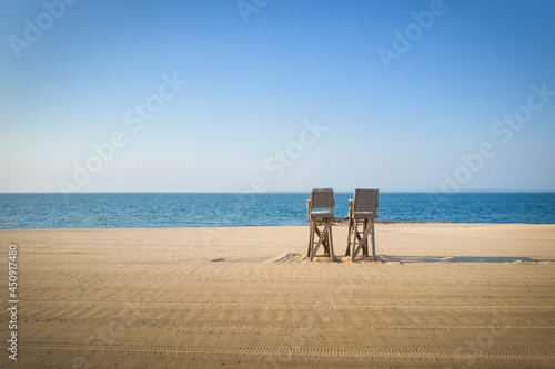 Tranquil seascape with two empty Lifeguard Chairs on the beach. Cape Cod Seascape in the early summer morning. Tranquil beachscape with clean sand. © Naya Na