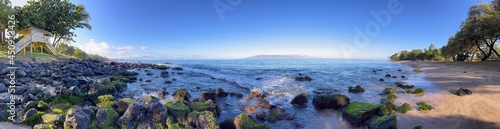Ocean waves lap the golden shores and seaweed-strewn rocks of Ka'anapali Beach in Lahaina, Hawaii. 