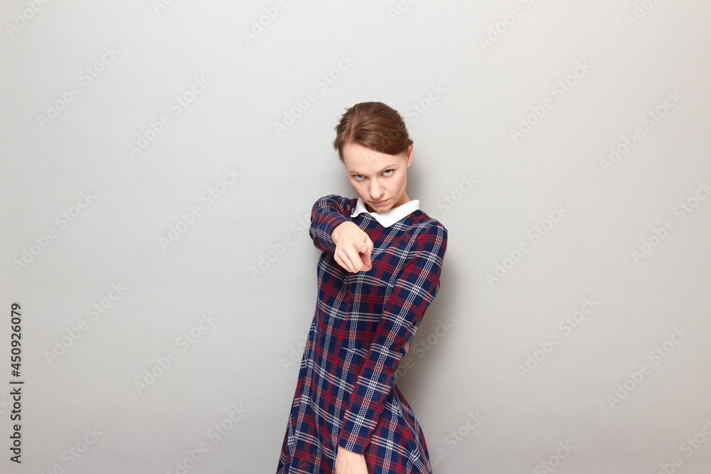 Portrait of serious girl pointing with index finger at you Portrait of serious girl pointing with index finger at you