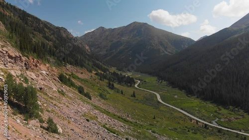 Wallpaper Mural Colorado mountain peaks summer view aerial drone forward over rock cliffs with river in valley of forest with car driving  on scenic road united states national forest blue sky white clouds elevation Torontodigital.ca