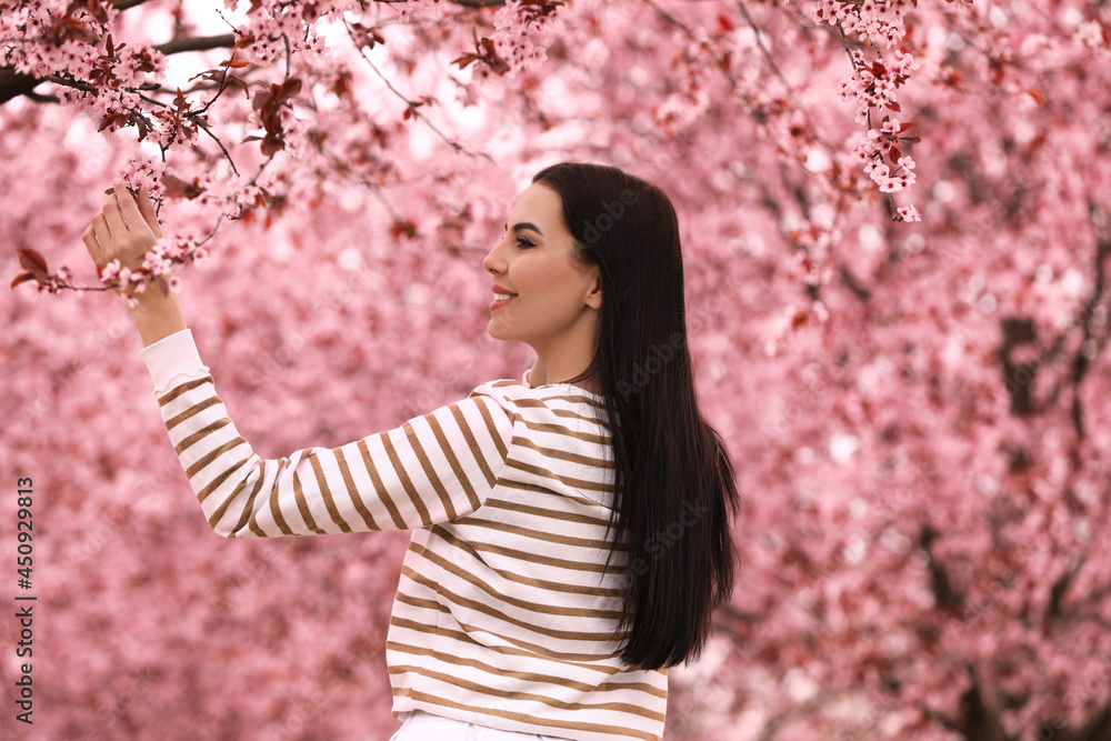 Pretty young woman in park with blooming trees. Spring look Pretty young woman in park with blooming trees. Spring look