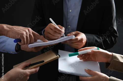 Man signing autograph in notebooks on dark background, closeup