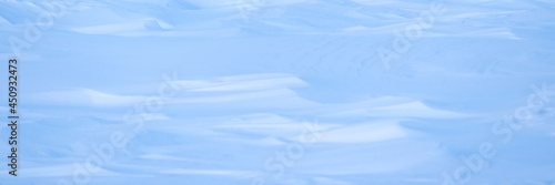 Beautiful winter background with snowy ground. Natural snow texture. Wind sculpted patterns on snow surface. Arctic, Polar region.