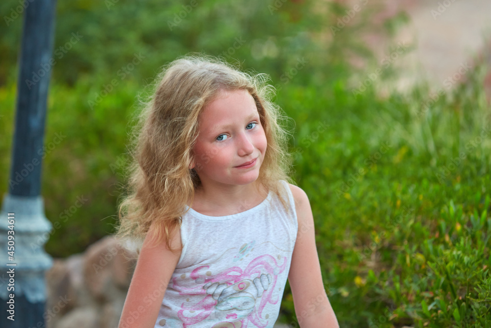 portrait of baby girl on background of greenery. Girl posing against background of summer greenery. Portrait of little girl portrait of baby girl on background of greenery. Girl posing against background of summer greenery. Portrait of little girl