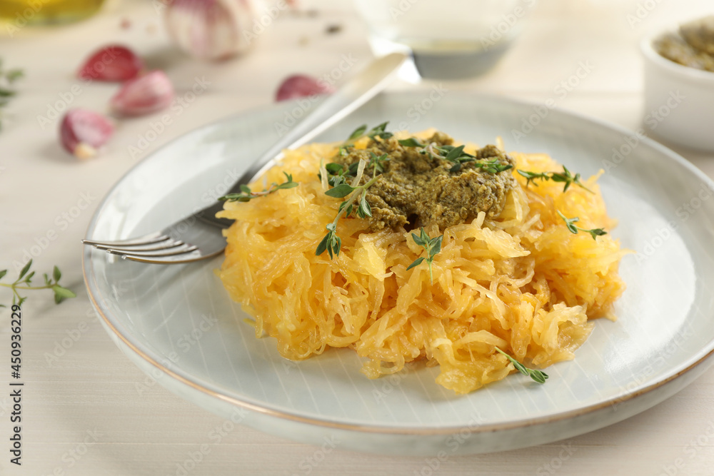 Tasty spaghetti squash with pesto sauce and thyme served on white wooden table Tasty spaghetti squash with pesto sauce and thyme served on white wooden table
