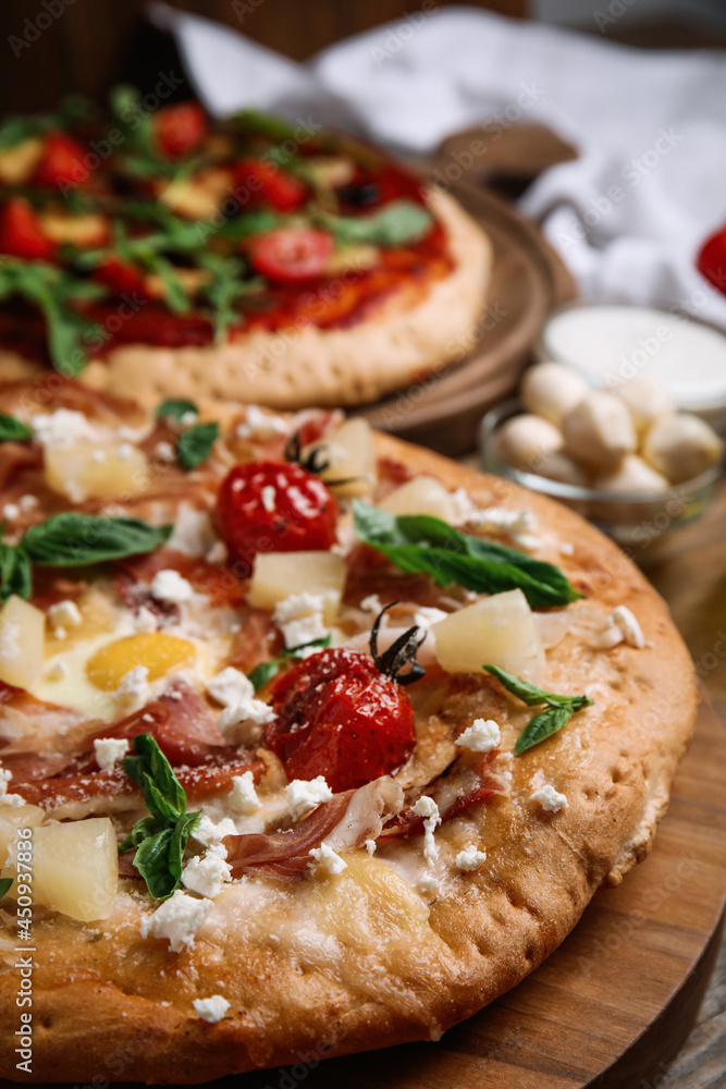 Pita pizza with prosciutto, pineapple, grilled tomatoes and egg on wooden tray, closeup Pita pizza with prosciutto, pineapple, grilled tomatoes and egg on wooden tray, closeup