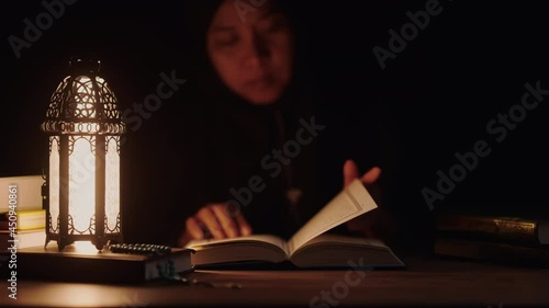 Asian Muslim woman reading the Quran and appreciates and faith The Holy Al Quran with written Arabic calligraphy meaning of Al Quran, Arabic word translation: The Holy Al Quran.