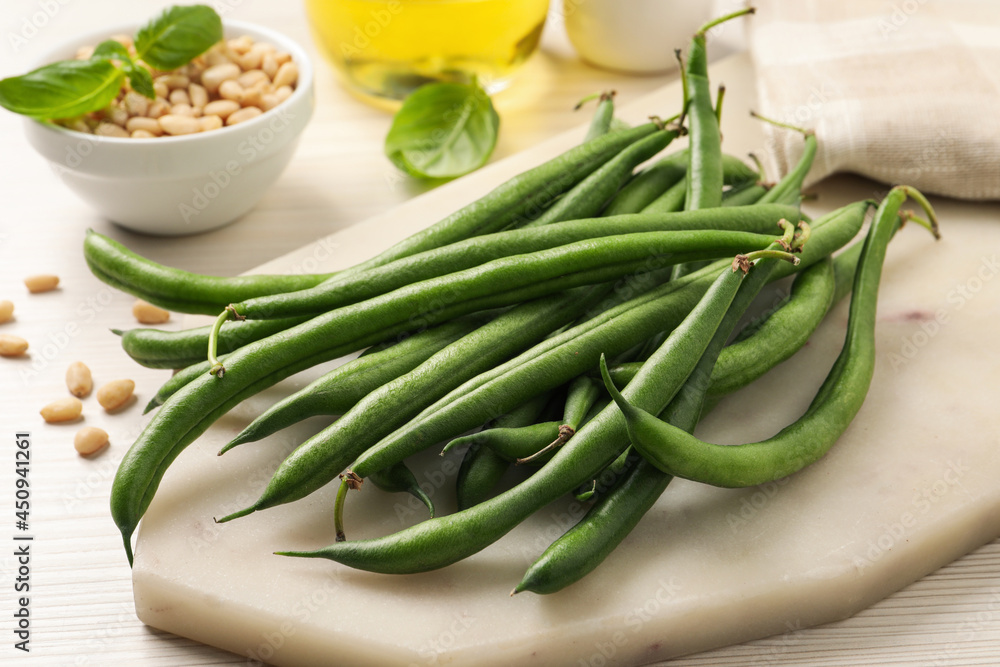 Board with fresh green beans on white wooden table Board with fresh green beans on white wooden table