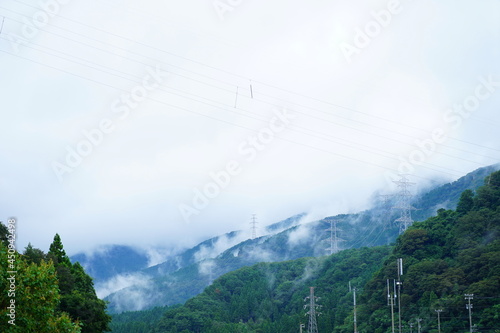 雲がかる山々と送電鉄塔