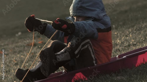Boy gets ready to sled down a hill with no snow