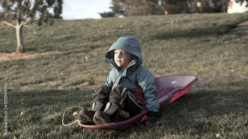 Boy on a green hill waiting for snow
