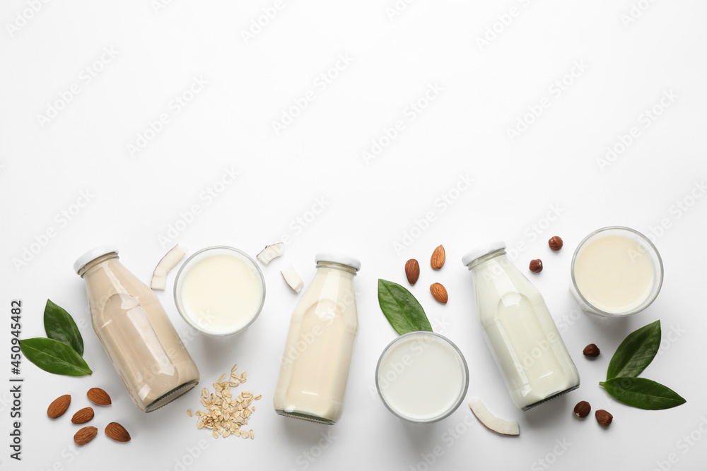 Different vegan milks and ingredients on white background, flat lay. Space for text Different vegan milks and ingredients on white background, flat lay. Space for text