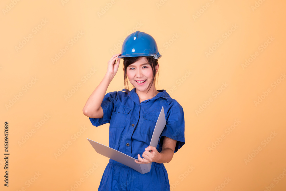 Young Asian female engineer working deliberately isolated on yellow background.	
