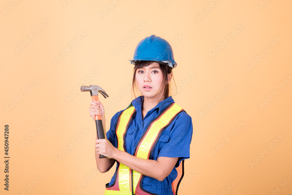 Portrait woman mechanic checking on yellow background