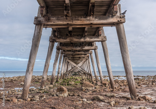 Tableau sur toile Underneath an old wooden jetty at a rocky beach at Port Hughes, South Australia