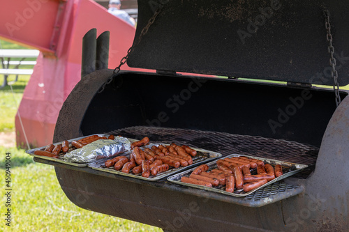 Hot dogs grilling at the park.