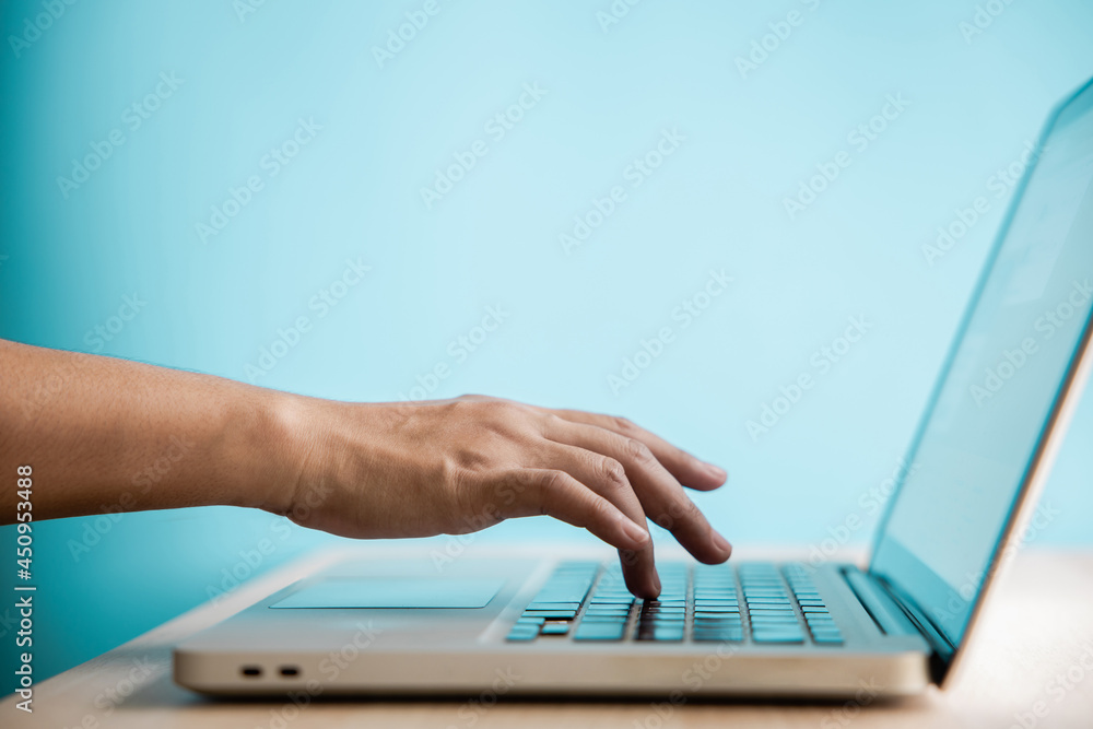 Hand Pressing Computer Keyboard. Side View. Closeup shot and Selective Focus on Finger. Person using Laptop for Working on Desk against the Blue Wall. Clean and Minimal photo Hand Pressing Computer Keyboard. Side View. Closeup shot and Selective Focus on Finger. Person using Laptop for Working on Desk against the Blue Wall. Clean and Minimal photo