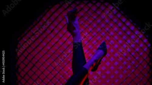 Close up of the legs beautiful sexy woman posing and dancing in knee high heels . Silhouette of female legs in high-heeled shoes on a background of lilac light. Holding up woman's legs . Slow Motion