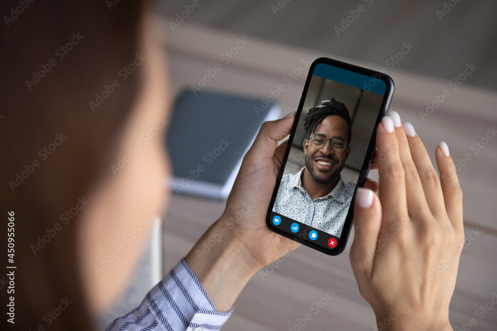 Φωτογραφία Close up view of young woman hold use cellphone talk speak on video call with African American man