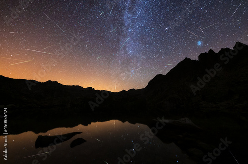 Perseidas meteoros sobre un lago reflejo y vía láctea photo