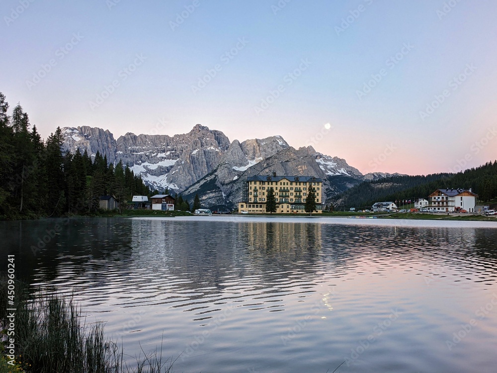 Fototapeta premium morning mood at lake misurina in the dolomites. morning dawn with the moon over the mountain peaks, tre cime lavaredo