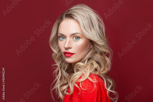 Blonde curly long hair woman with beauty makeup over red background
